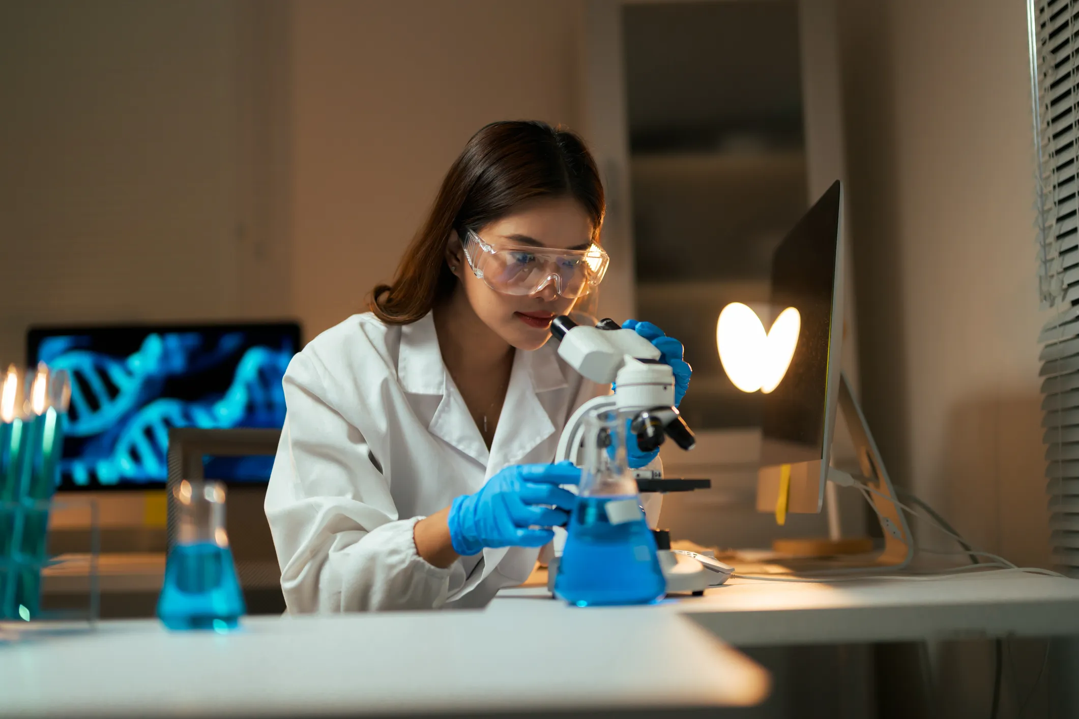 Scienziato al microscopio guarda DNA